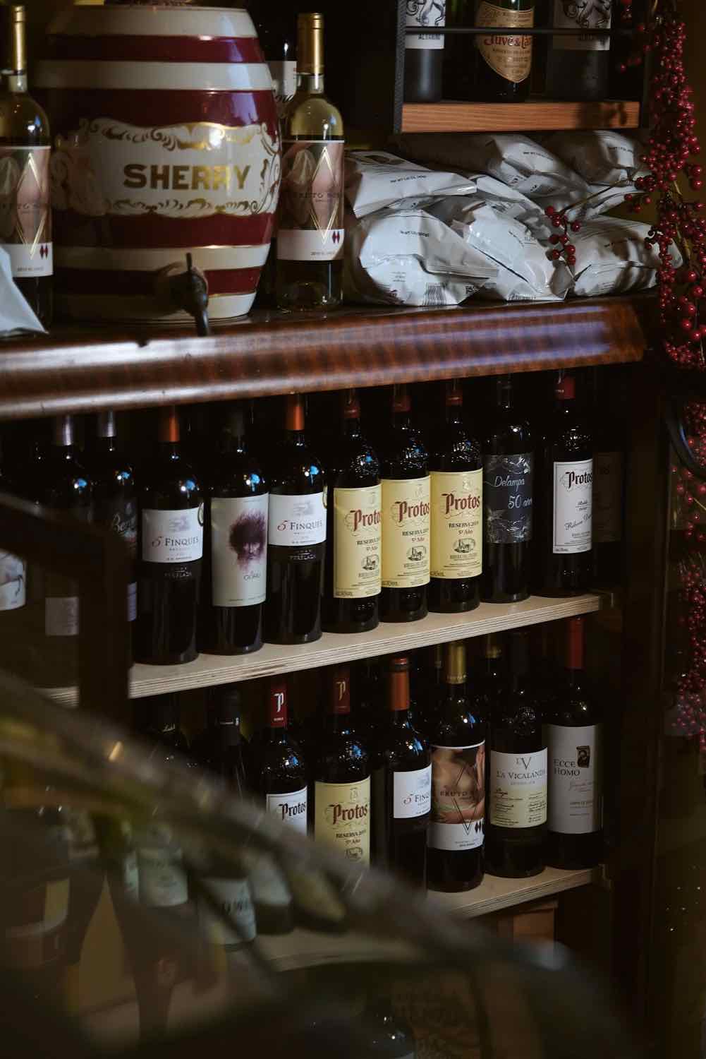 Shelves of wine and a barrel behind the bar at Piggs