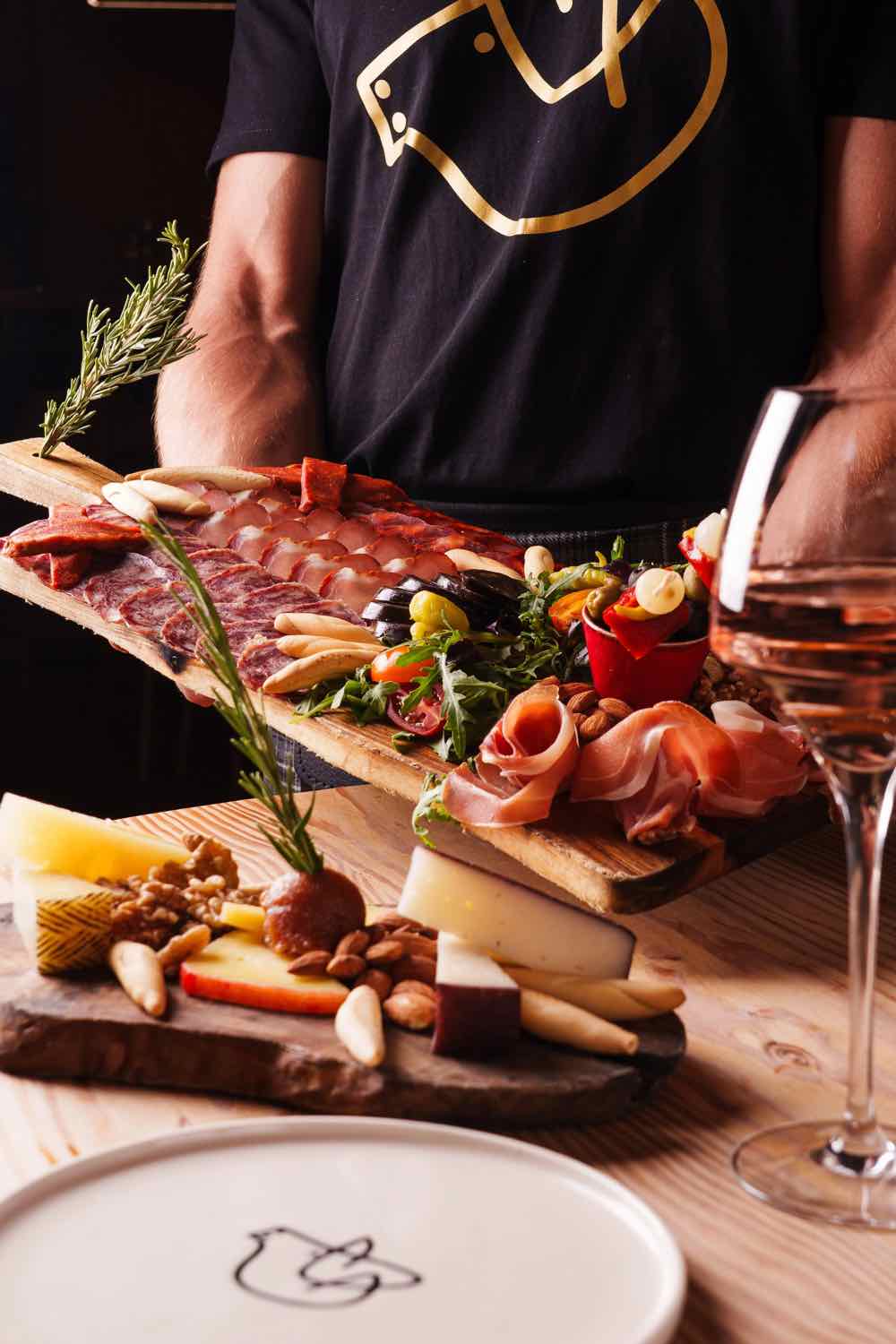 Piggs staff presenting a laden charcuterie board to a table