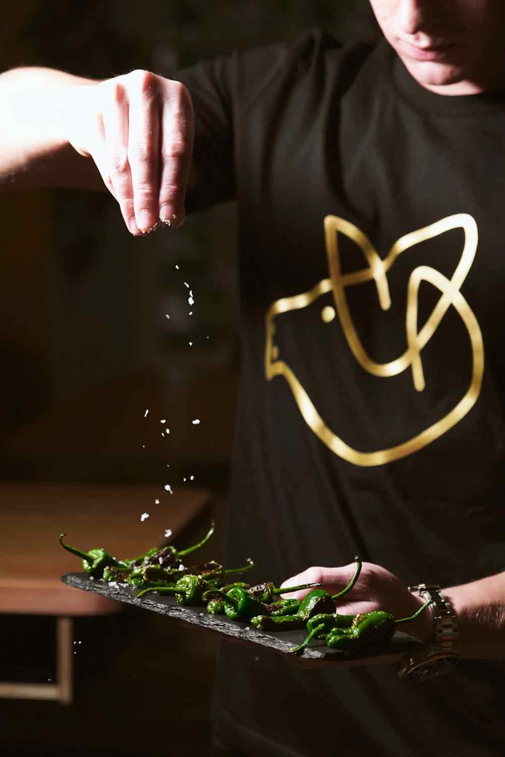 A chef finishing a dish with a flourish at Piggs