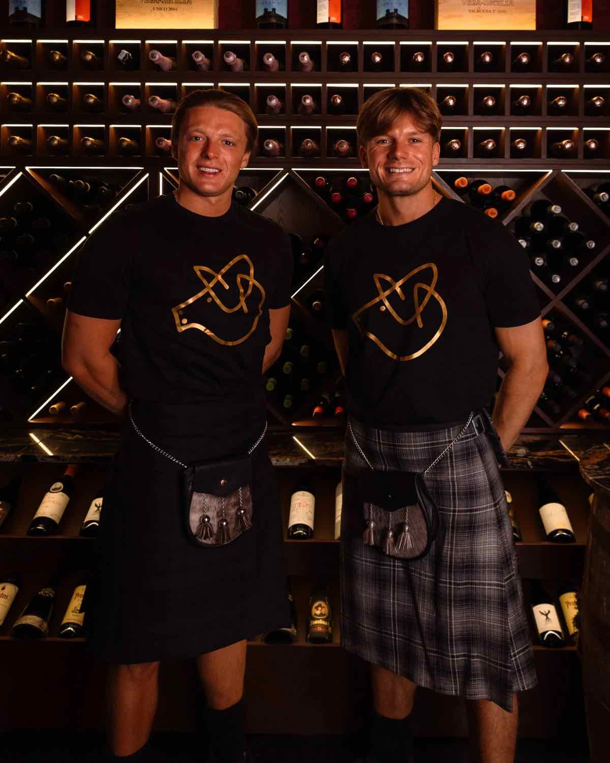 The Campos brothers in black Piggs t-shirts in front of the wine wall
