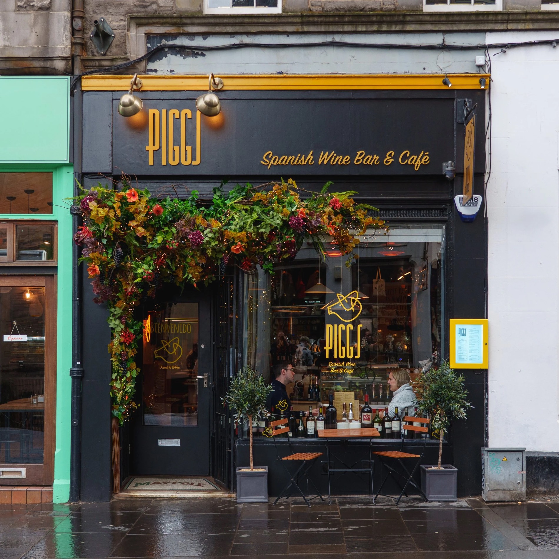The black-and-gold Piggs shopfront on the Royal Mile, framed with flowers